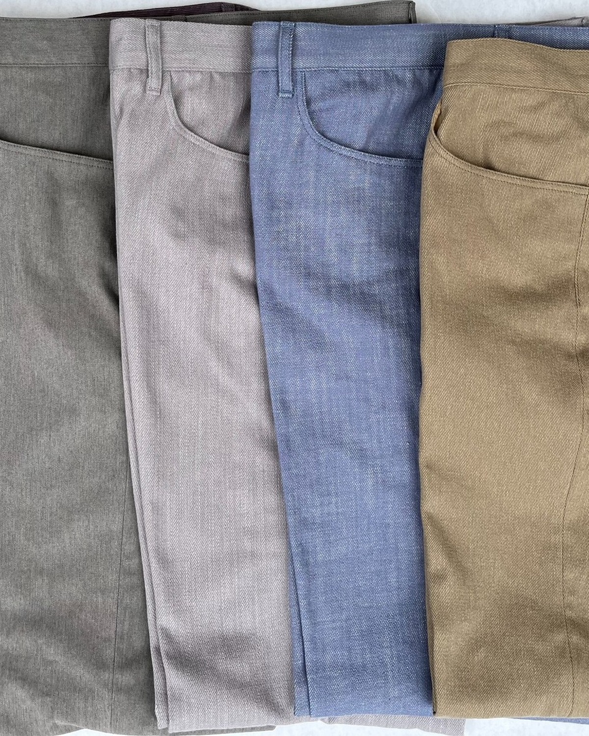 A close arrangement of finished trousers in varied cloths